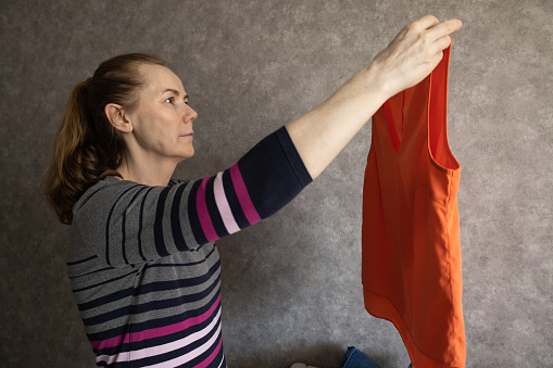 Woman checking different clothes from the closet to pick outfit
