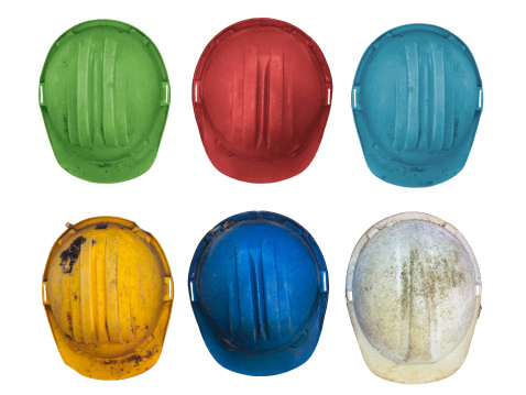 Old and worn colorful construction helmets isolated on white