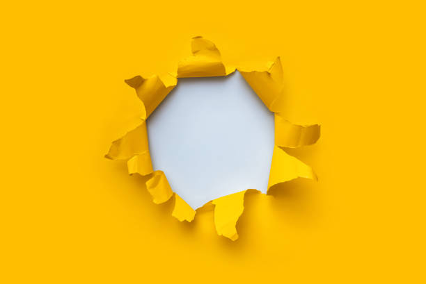 Torn hole in yellow paper with white empty background. Copy space, mockup. Place for text or logo. stock photo