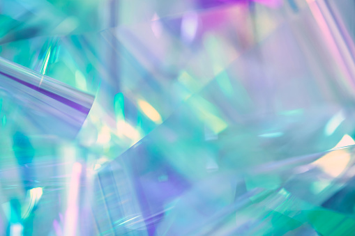 Soft focused, blurred close-up of ethereal pastel neon mint, turquoise, blue, purple holographic metallic foil background. Abstract modern sparkle surreal futuristic disco, rave, dreamlike backdrop