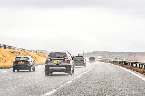 South Lanarkshire, Scotland - Cars driving south on the M74 motorway producing spray from water on the road surface during wet conditions.