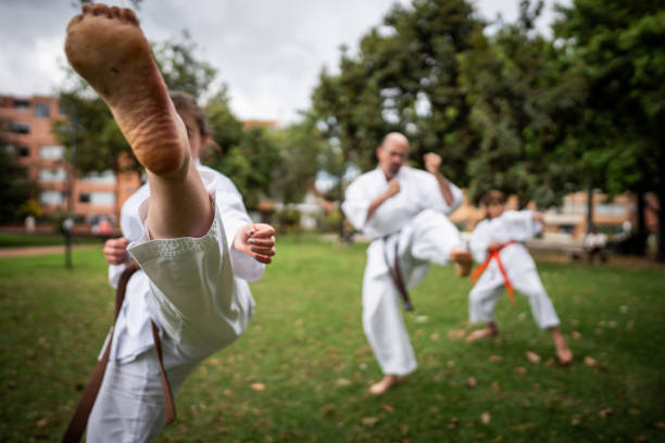 estudiantes de karate / taekwondo practicando movimientos de patada en un parque público - sole of foot martial arts karate female fotografías e imágenes de stock