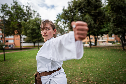 Teenage girl practicing karate/taekwondo movements at public park
