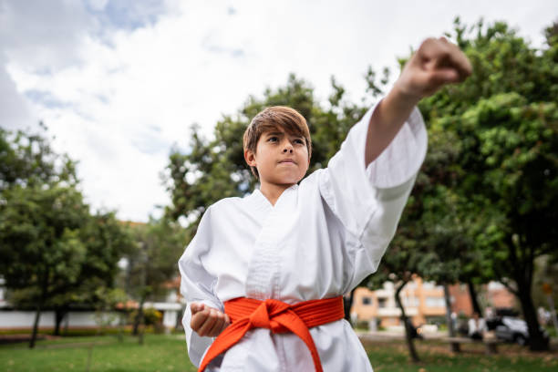 Child boy practicing karate/taekwondo movements at public park