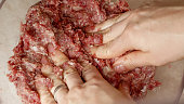 Closeup of female hand beating and mixing minced meat with spices. Cooking at home, kitchen appliance, healthy nutrition, hamburger ingredients.