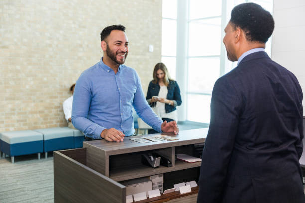 istock Businessman smiles at teller before picking up his cash 1569975865