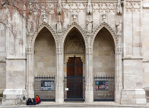 VIENNA, Austria - January 6, 2023: Two girls and a white bicycle in front of an entrance of the neo-gothic Votive Church