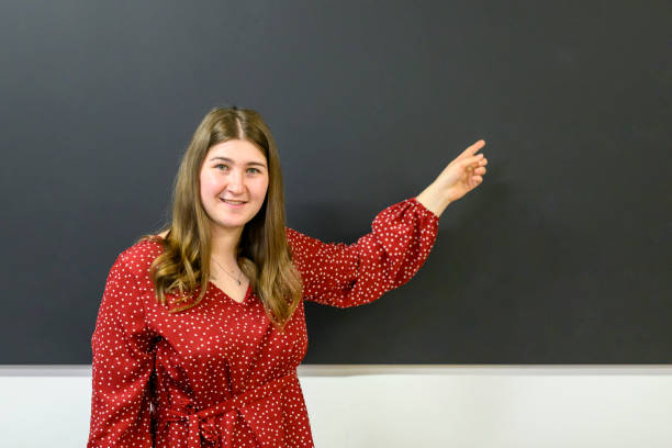 istock Smiling teacher showing something at the blackboard 1570005321