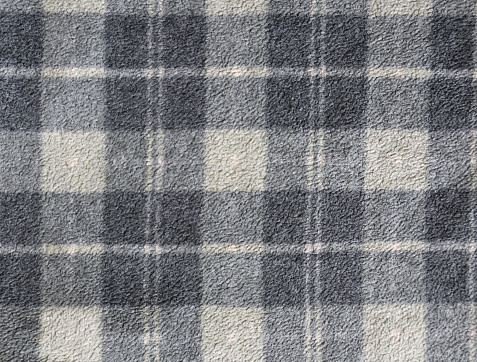 Fleece texture background with plaid pattern of grey dark grey and light grey colors. Gray fleece fabric texture with checkered pattern