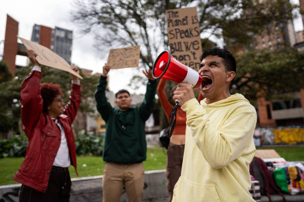 istock Young man shouting on megaphone on an environmental protest outdoors 1570020475