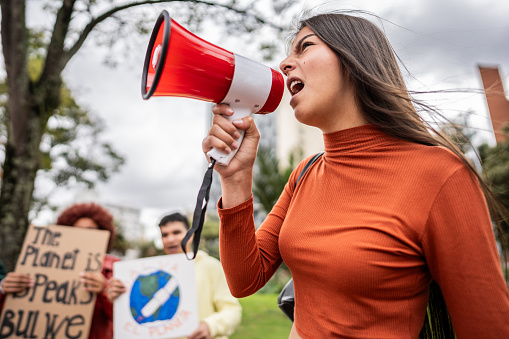 Teenage girl shouting on megaphone on an environmental protest outdoors
