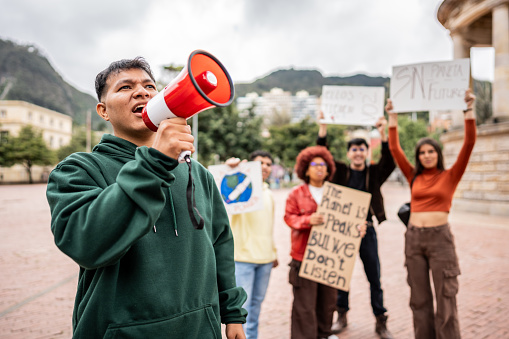 Young man shouting on megaphone on an environmental protest outdoors