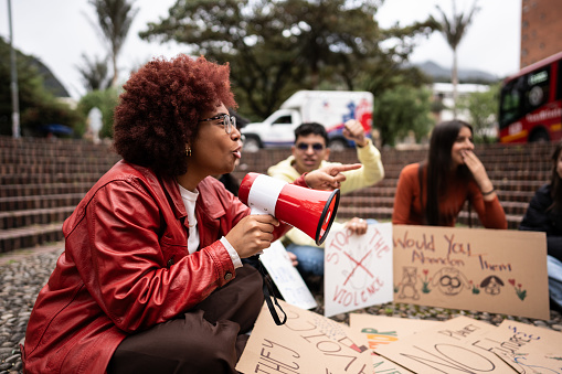 Young woman leading a demonstration using a megaphone outdoors