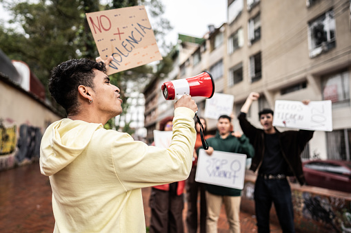 Young protester man leading a demonstration using a megaphone outdoors