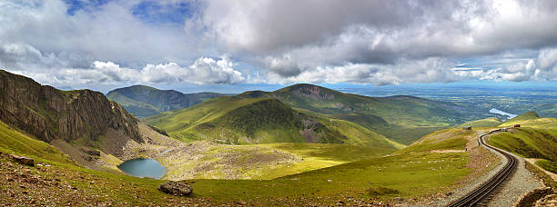 Snowdonia panorama Panorama of the mountains of Snowdonia looking from Mount Snowdon, with a vintage steam train climbing from the town of LLanberis to the summit. mount snowdon photos stock pictures, royalty-free photos & images