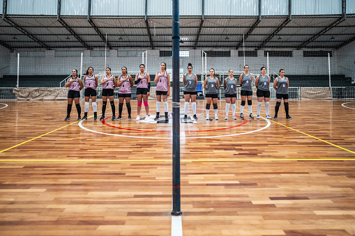 Female volleyball players singing the anthem before starting the match on the sports court