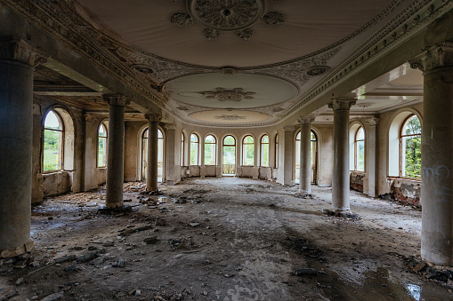 Large hall with columns in old abandoned mansion.