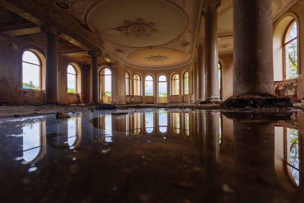 istock Flooded large hall with columns in old abandoned mansion, water reflection 1570092467