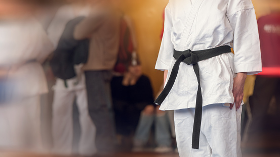 A martial arts athlete in a white kimano with a black belt is preparing for a fight. Color photo with motion blur effect.