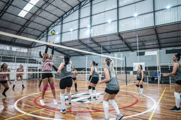 Female volleyball players playing a volleyball match on the sports court Female volleyball players playing a volleyball match on the sports court volleyball sport stock pictures, royalty-free photos & images