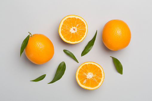 Flat lay with fresh oranges and leaves on color background.