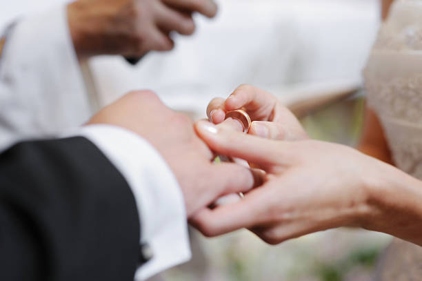 istock Bride putting a ring on groom's finger 157010828