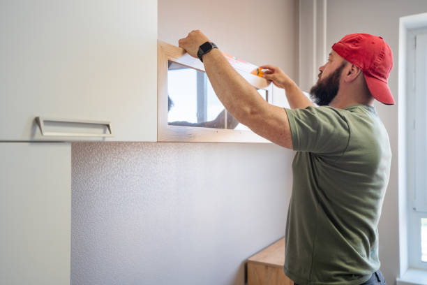 istock Man examining the installed shelves with a construction level 1570124265