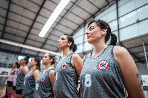 Female volleyball players singing the anthem before starting the match on the sports court