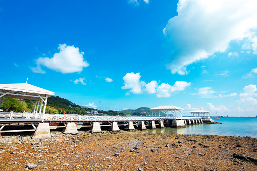 Side panorama of Historical  wooden  pier สะพานอัษฎางค์ on Ko Sichang island into sea in Chonburi province. Pier is historical attraction near Phra Chutha Thut Rat Than Museum from around 1900 at east coast