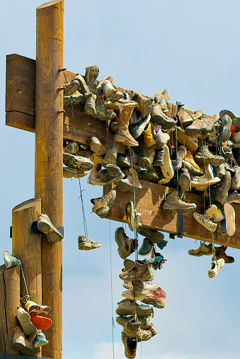 Cimarron, New Mexico, USA - July 24, 2023: Dozens of pairs of hiking and cowboy boots hang from the main entrance sign at the Boy Scouts of America’s Philmont High Adventure Base in northern New Mexico, following a long tradition.