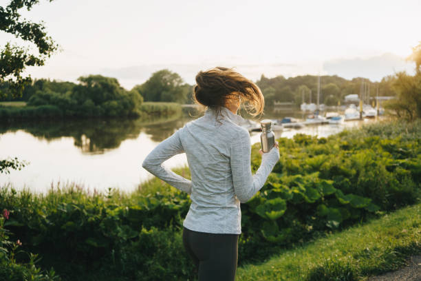 istock Woman  running along the river at sunset 1570184098