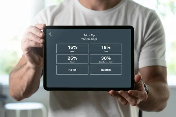 Photo of Man holding a tablet with tipping screen inside a restaurant