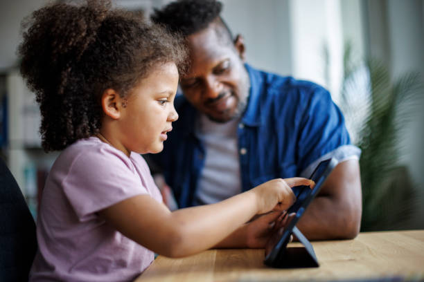 istock African American father and adorable mixed race daughter using digital tablet at home 1570186828