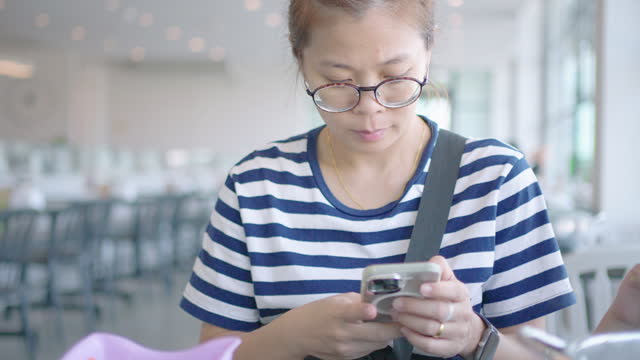 Asian woman using a smartphone ordering menu from smartphone at the restaurant