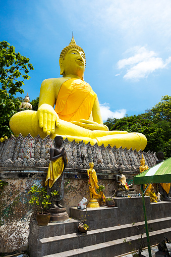 View up big golden thai buddha at Tham Chakkaphong Sangha Monastery on island Ko Sichang, monastery is quiet isolated place with religious cave below too. Island is in Chonburi province