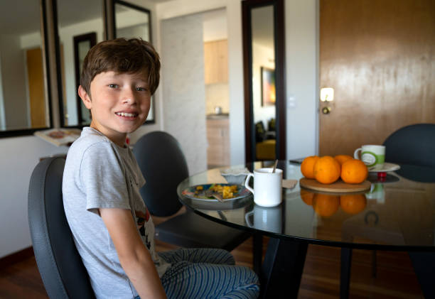 istock Boy drinking orange juice and eating eggs for breakfast 1570208632