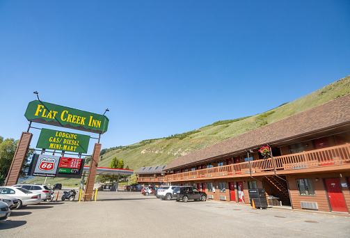 People, cars and commercial signs visible near Flat Creek Inn on Highway 89 at Jackson (Jackson Hole) in Teton County, Wyoming