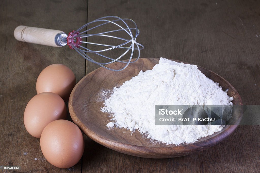 Uova e farina in un piatto di legno della vecchia Quercia tabella - Foto stock royalty-free di Alimentazione non salutare