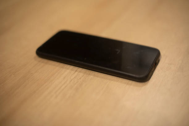 istock Smartphone on table. Black phone. Device lies on board. 1570258670
