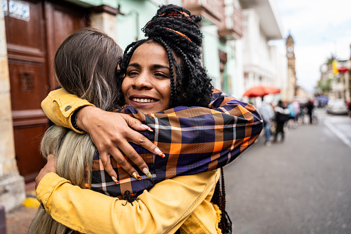 Female Friends greeting and embracing in historic district of Bogota, Colombia
