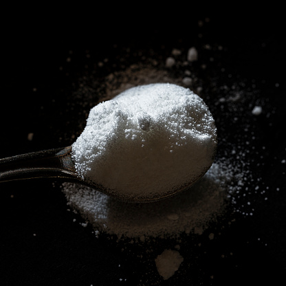 Dose of white powder on a spoon. Citrulline malate biohacking concept