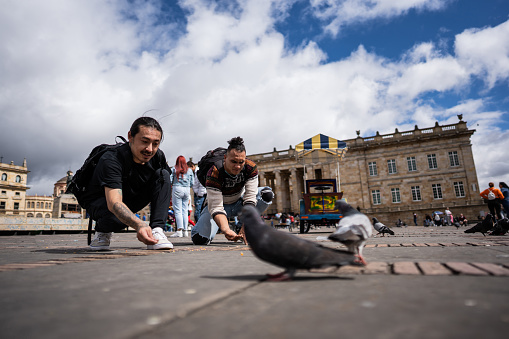 Friends feeding pigeons in historic district in the city