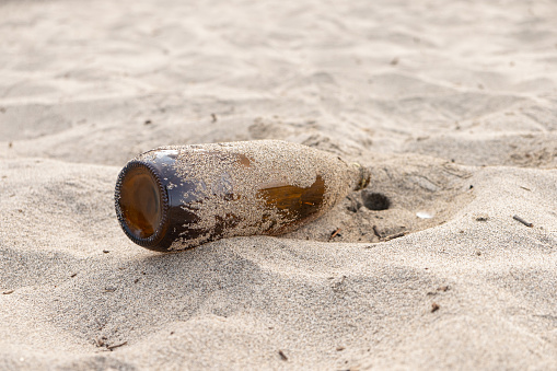 empty glass bottle of beer lying on a beach