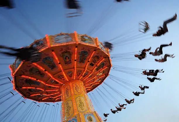 People on  a chain swing ride at an amusement park.