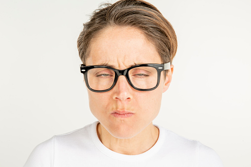 Adult woman portrait. Beautiful adult woman in glasses with short hair standing in front of white background in white t-shirt. Studio shoot. White People.
