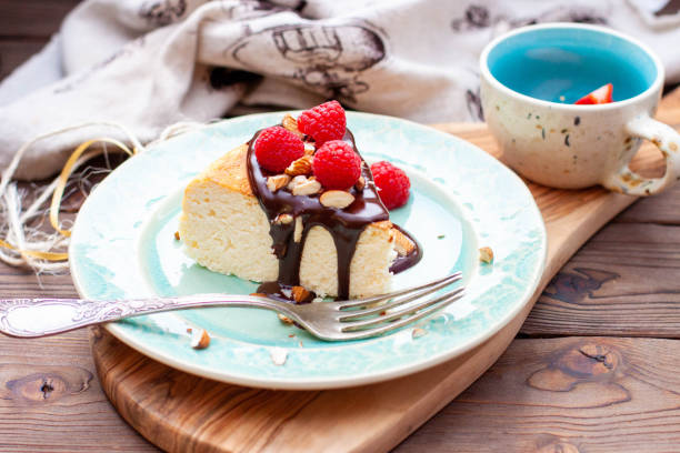 istock Slice of vanilla cheesecake with chocolate sauce, fresh raspberry and nuts on blue plate, close up view 1570303567