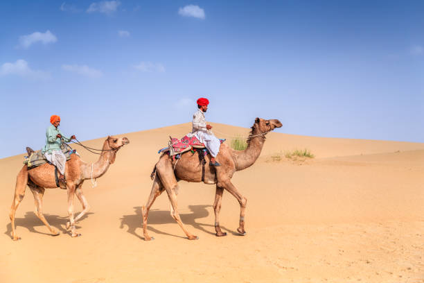 istock Indian men riding camels on sand dunes, Rajasthan, India 1570314645
