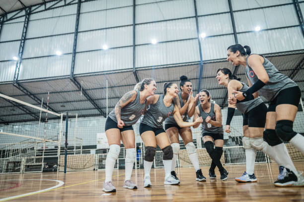 squadra di pallavolo femminile che festeggia dopo aver vinto una partita sul campo sportivo - team sport foto e immagini stock