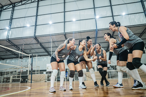 Female volleyball team celebrating after win a match on the sports court