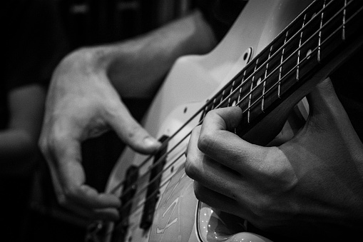 Close-up of man's hands playing bass guitar. Person playing bass guitar. Guitar strings. Person playing rock. Musical instrument